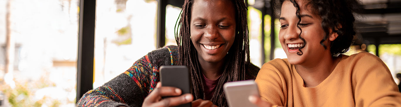 Two girls with phones laughing