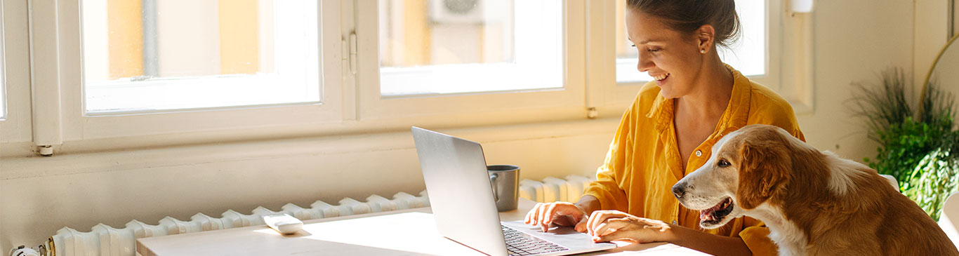 woman on laptop smiling with dog