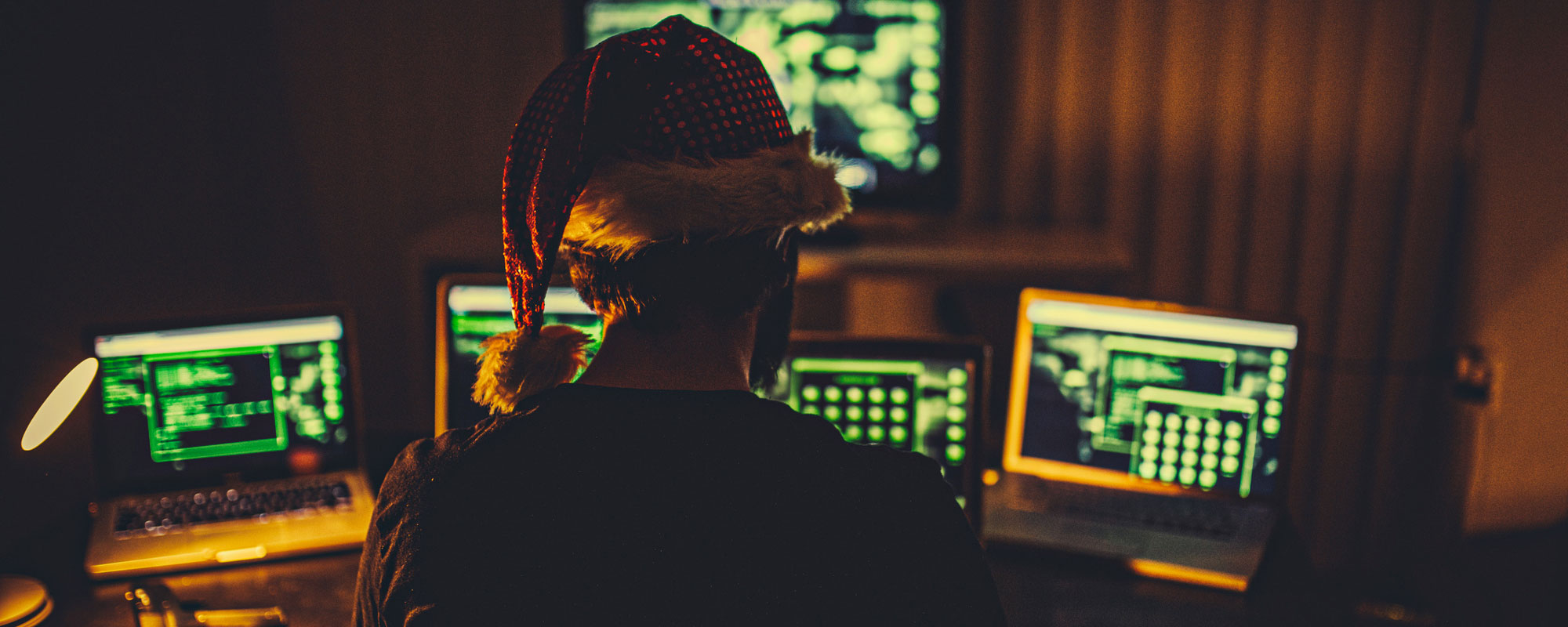 Hacker wearing Santa hat looking at computers