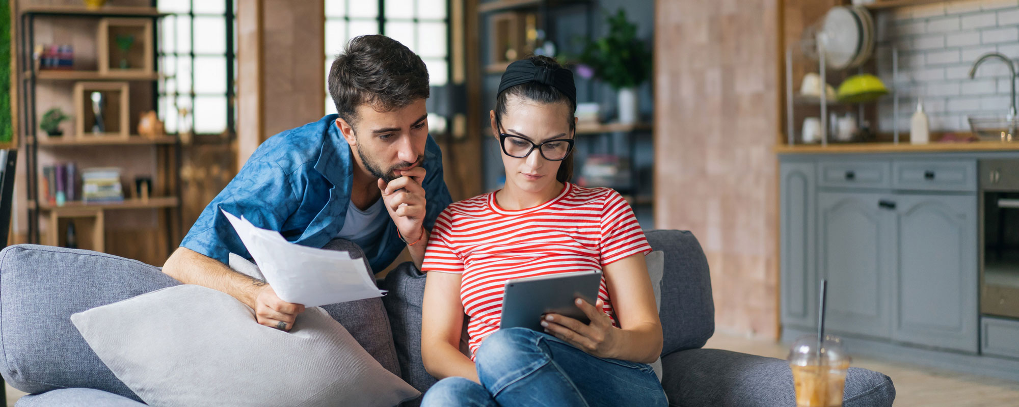 Couple calculating bills at home using tablet and calculator