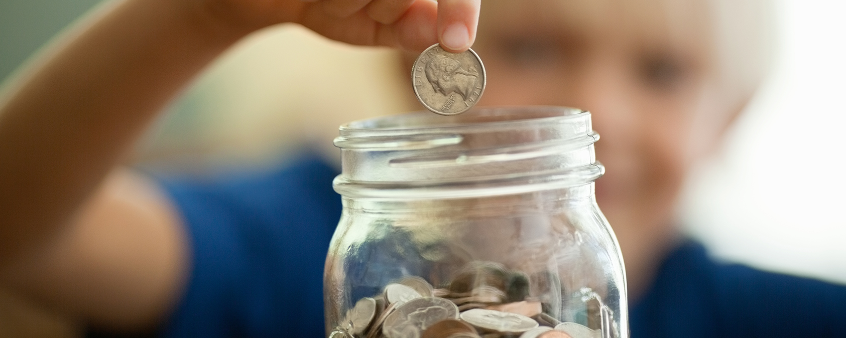 child putting coins in jar