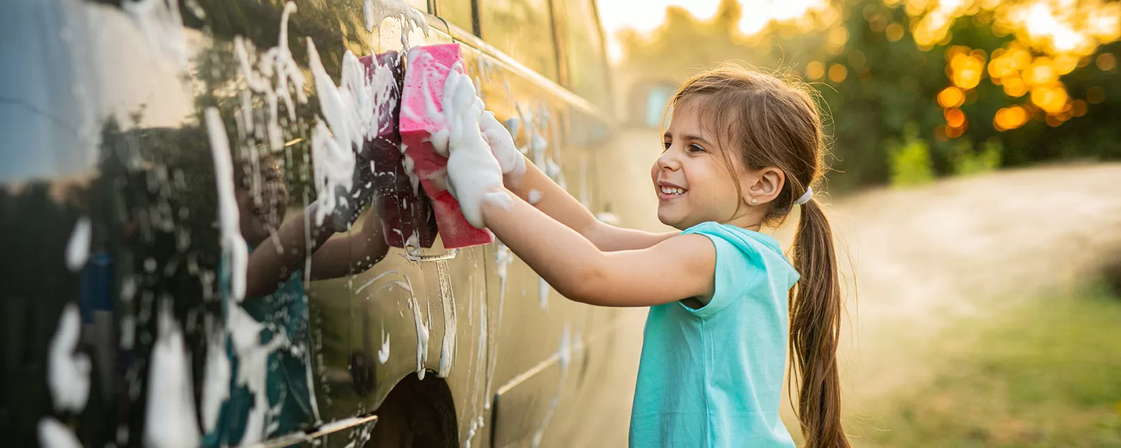 small girl washing the exterior of a car