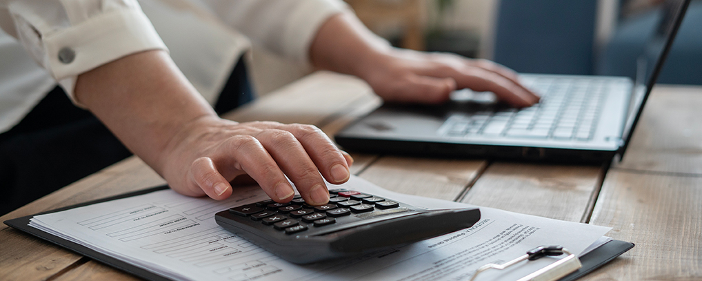 hand on keyboard and hand on calculator