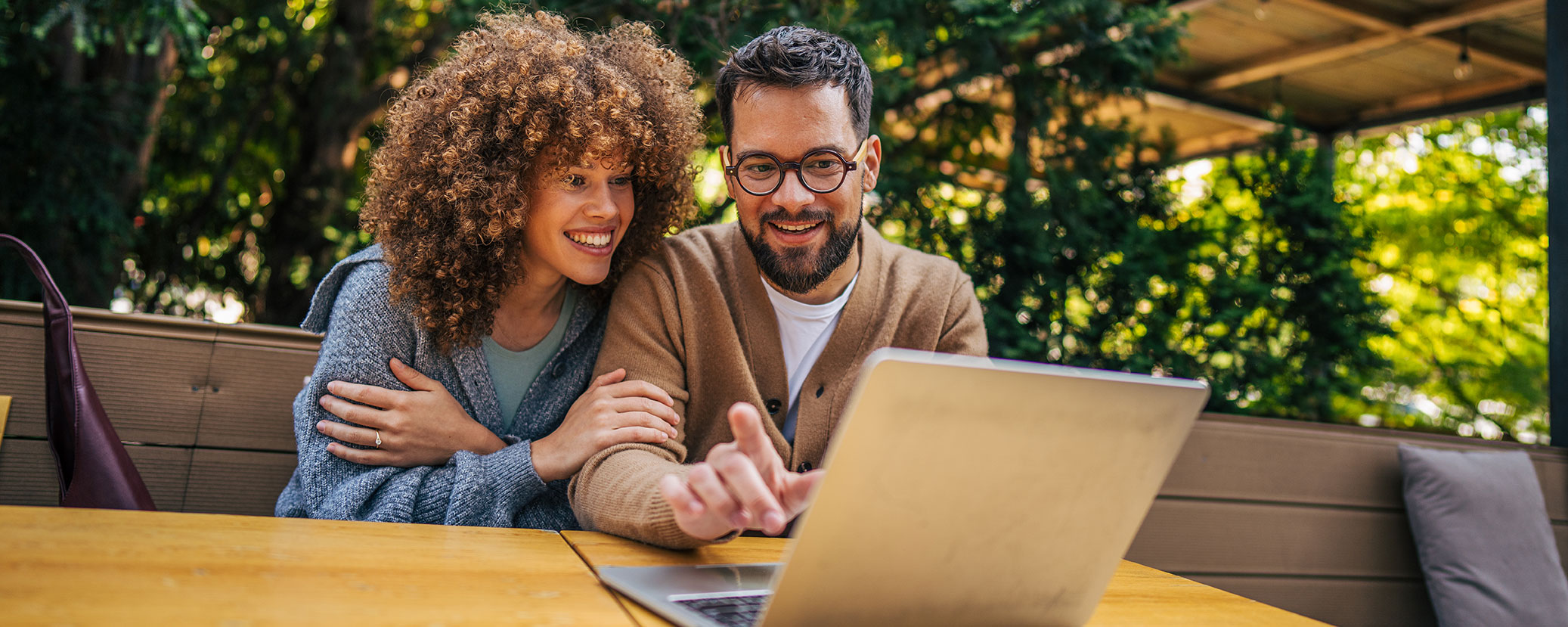 couple sitting out on patio looking at computer screen and smiling