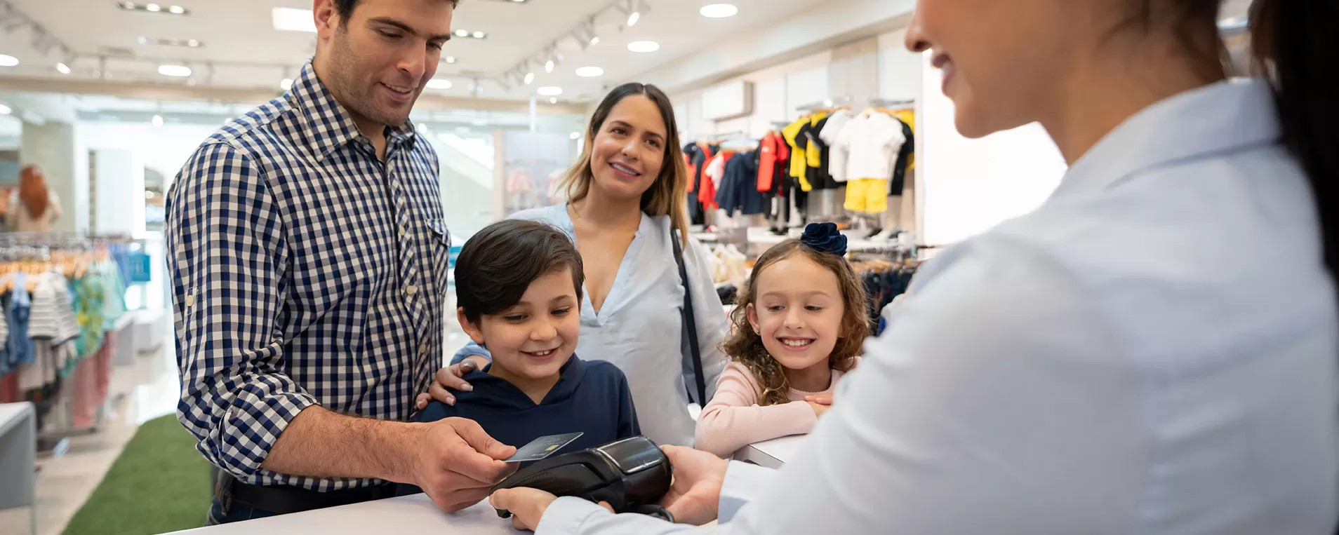 Man using rewards credit card at store while wife and children look on