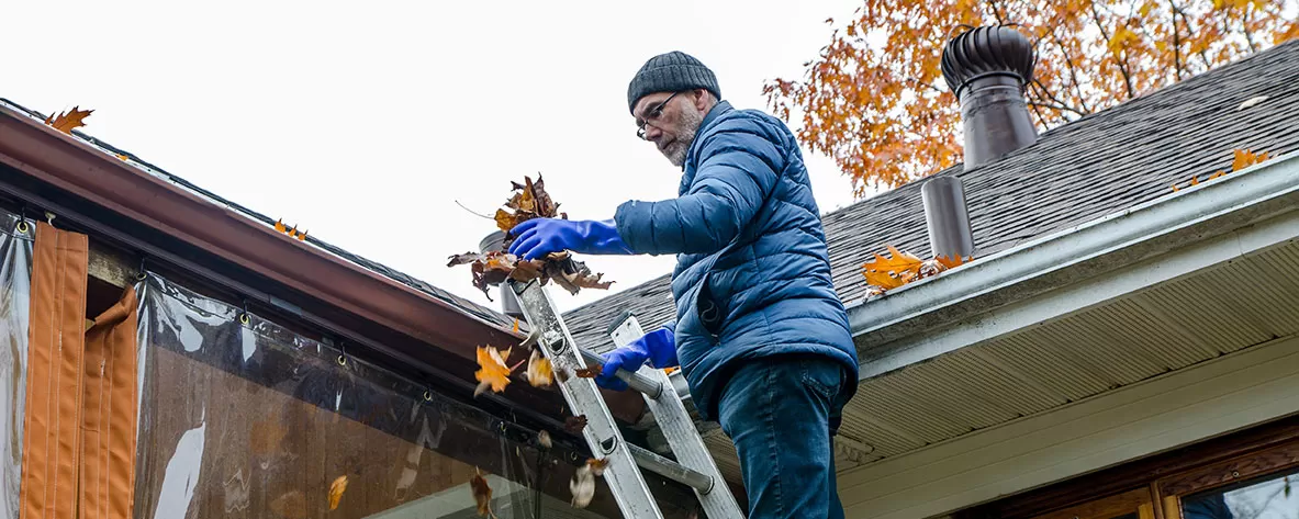 Man cleaning out gutters in preparation of weather