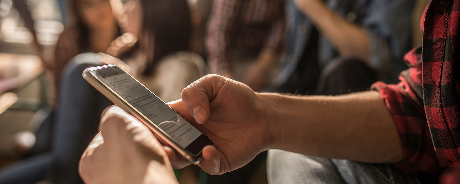 mobile phone up close with teenagers hangout out around