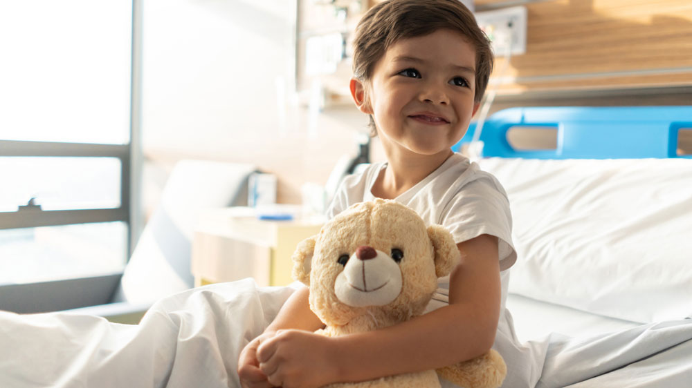 Little boy in hospital hugging teddy bear